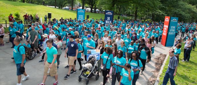 hundreds of people wearing teal shirts and walking YAI's Central Park Challenge