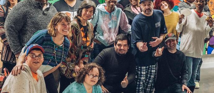 Large group of people pose in front of a colorful mural