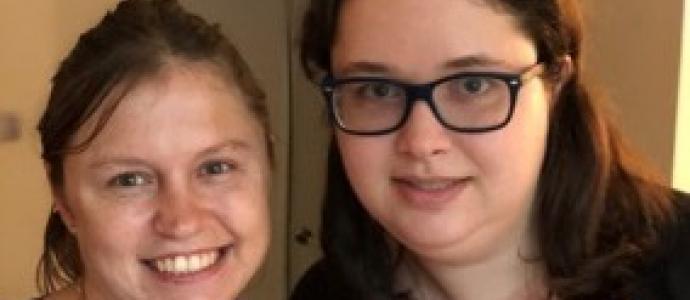 two women stand next to one another and smile for photo