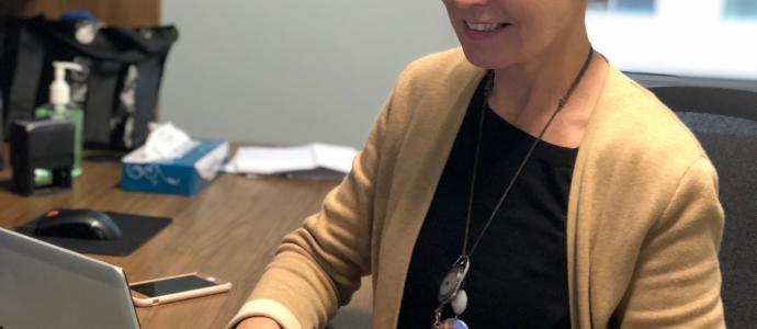 Woman sits at a desk with a laptop open in front of her