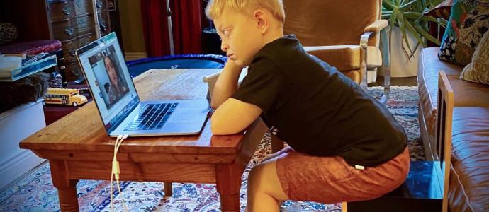 child sitting at a desk looking at a laptop