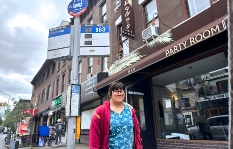 Lily stands at a bus stop in Brooklyn