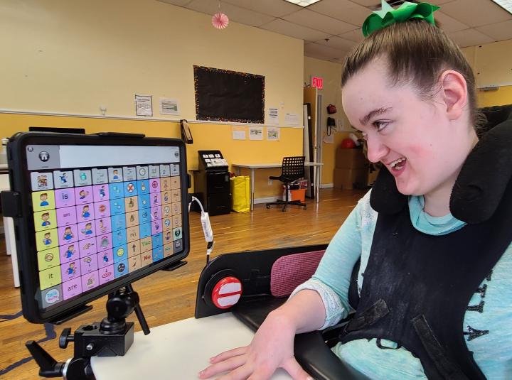 Amelia at her wheelchair, she is looking at the screen of the communication device she is using talk suite on