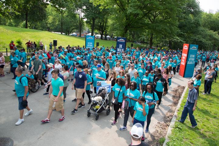 hundreds of people wearing teal shirts and walking YAI's Central Park Challenge