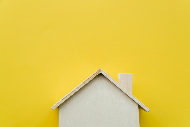 Miniature wooden house with yellow background