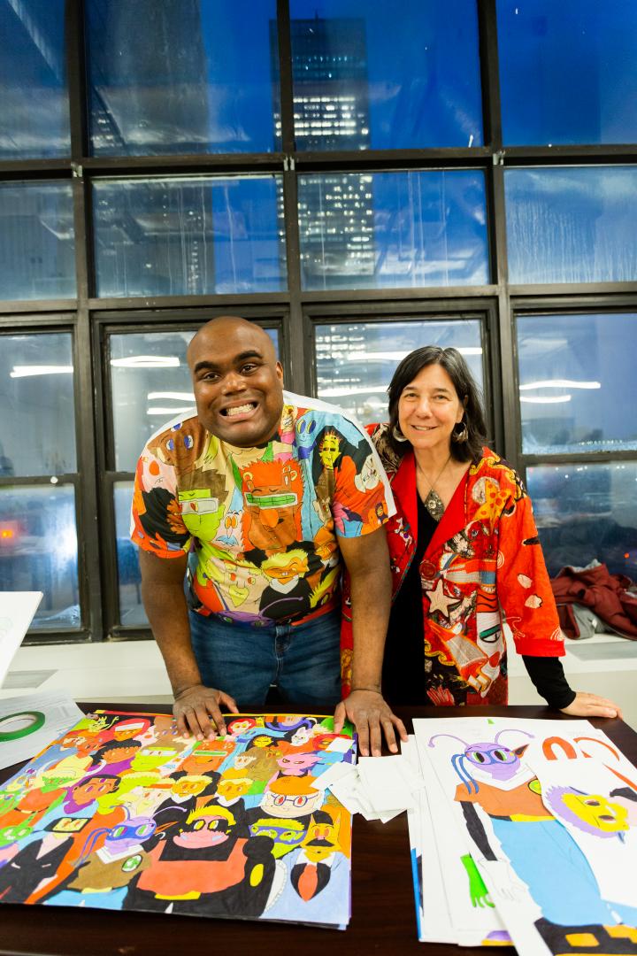 man and woman stand at table with artwork displayed