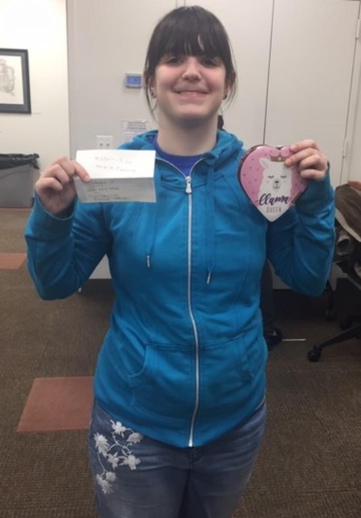 Amanda smiles while holding up an envelope and valentines heart