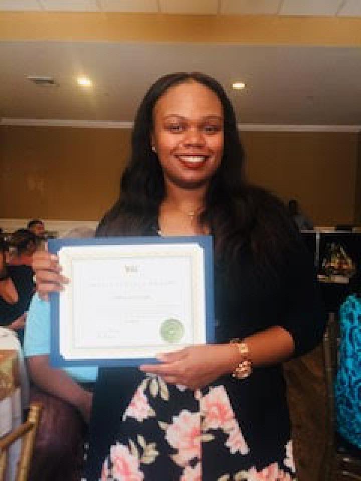 Photograph Erika Heyliger holding a certificate in front of her with both hands