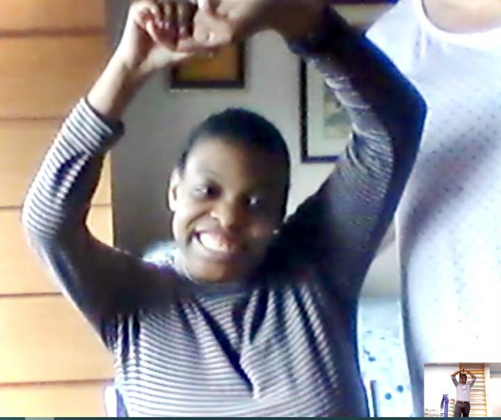 Ashley Walters raises her hands while her mother ensures her stability during a physical therapy session