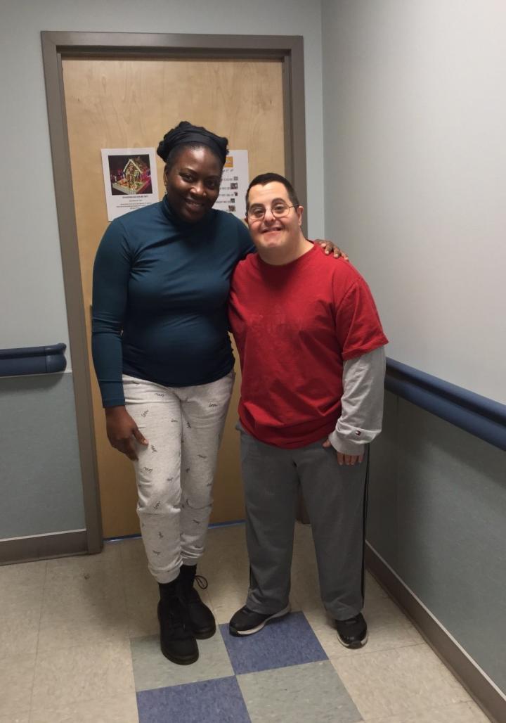 Two people stand in front of a door and pose/smile for picture