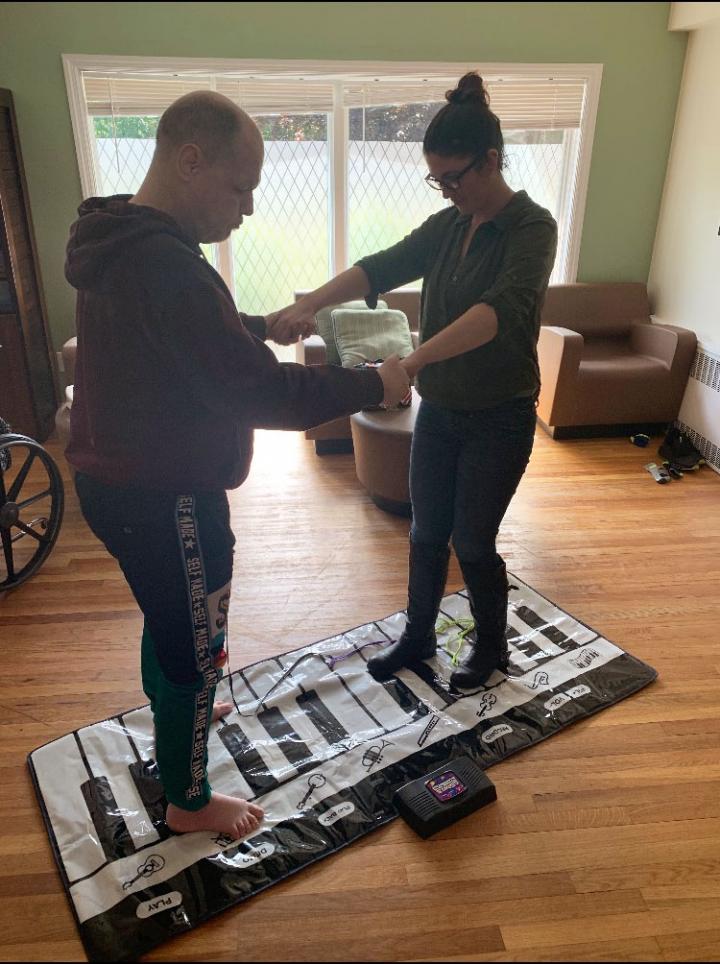 Emily and Craig stand on a floor piano together, holding hands