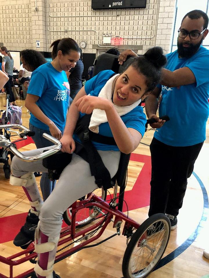 iHOPE student Maria celebrates after she completes an adaptive cycling race.