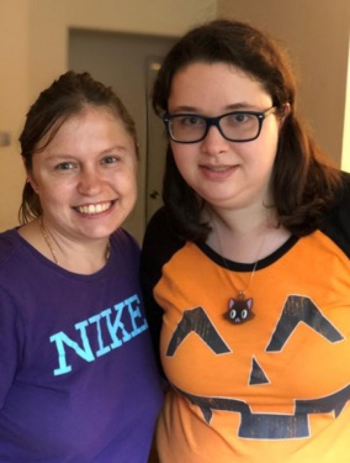 two women stand next to one another and smile for photo