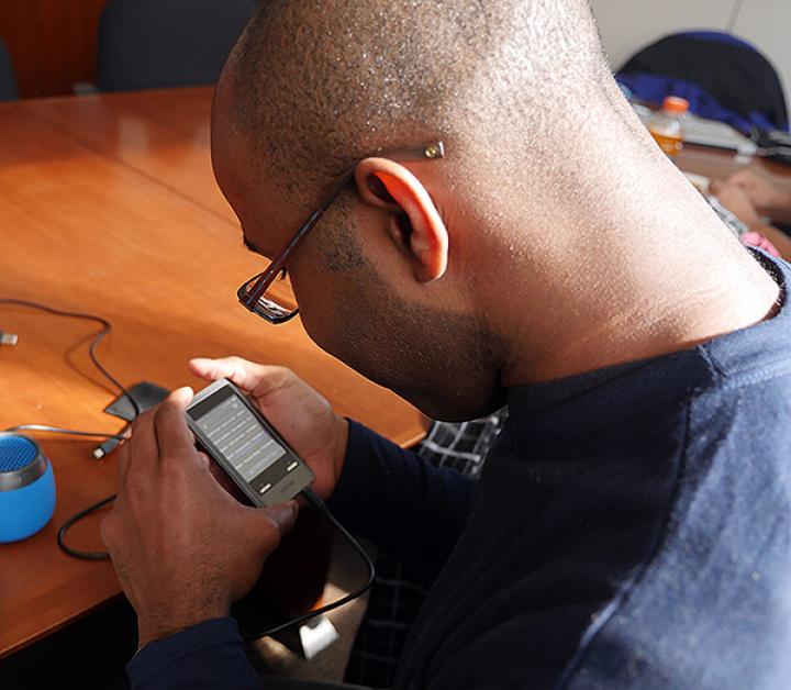 Picture shows a person wearing glasses using a tech device