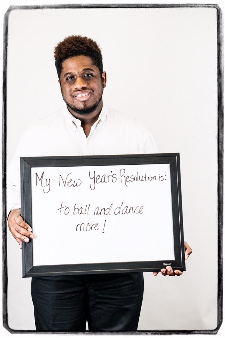 Photograph of man holding sign "My New Year's Resolution is: To ball and dance more!"