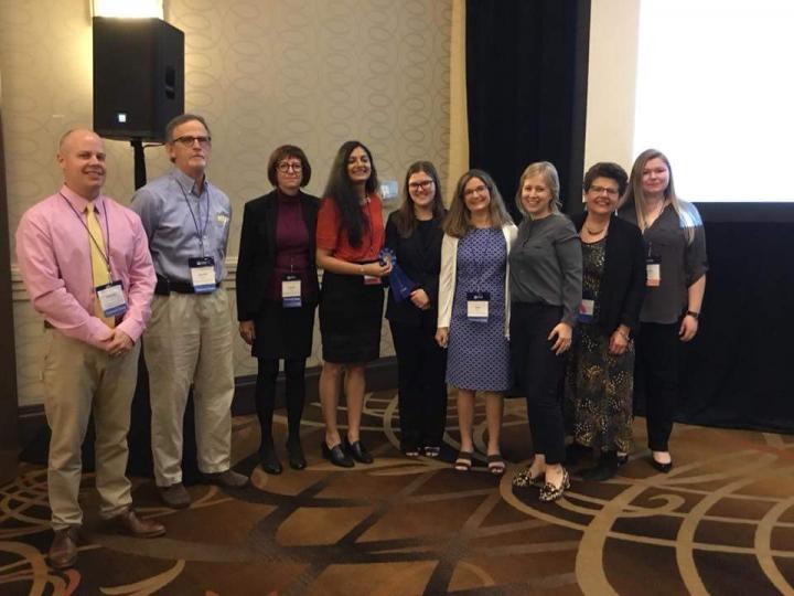 9 people pose for photo at conference