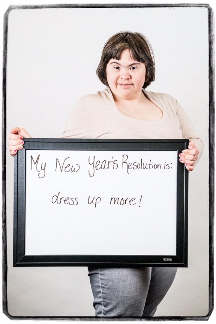 Photograph of woman holding sign "My New Year's Resolution is: dress up more!"