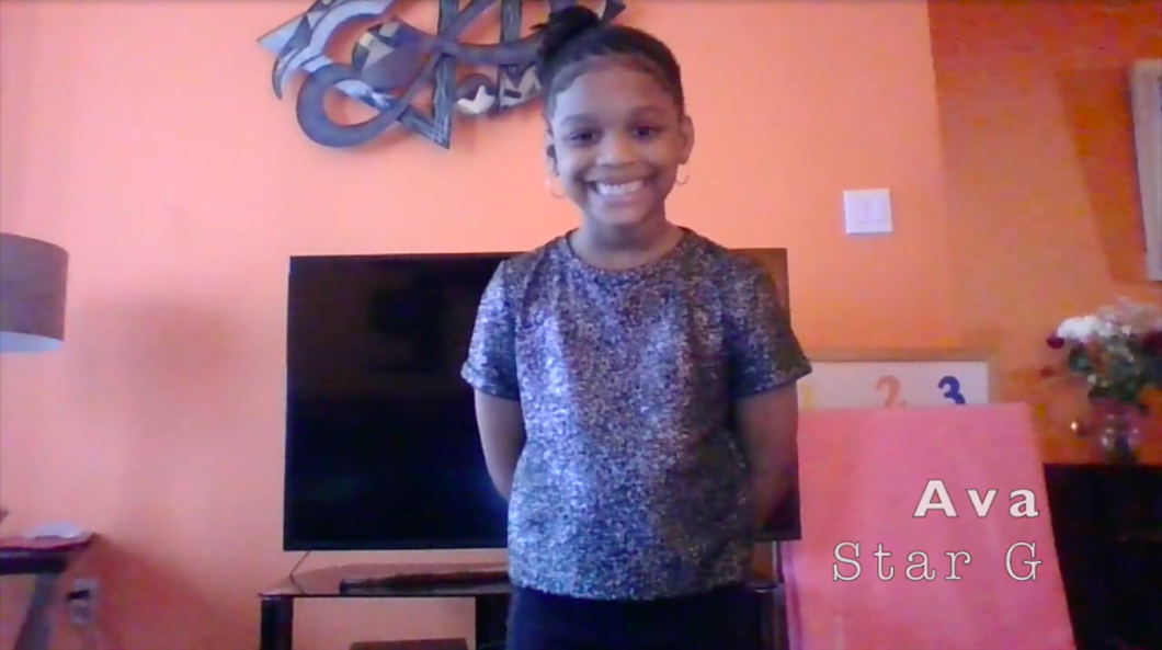 Manhattan Star Academy Student on zoom can be seen standing and smiling