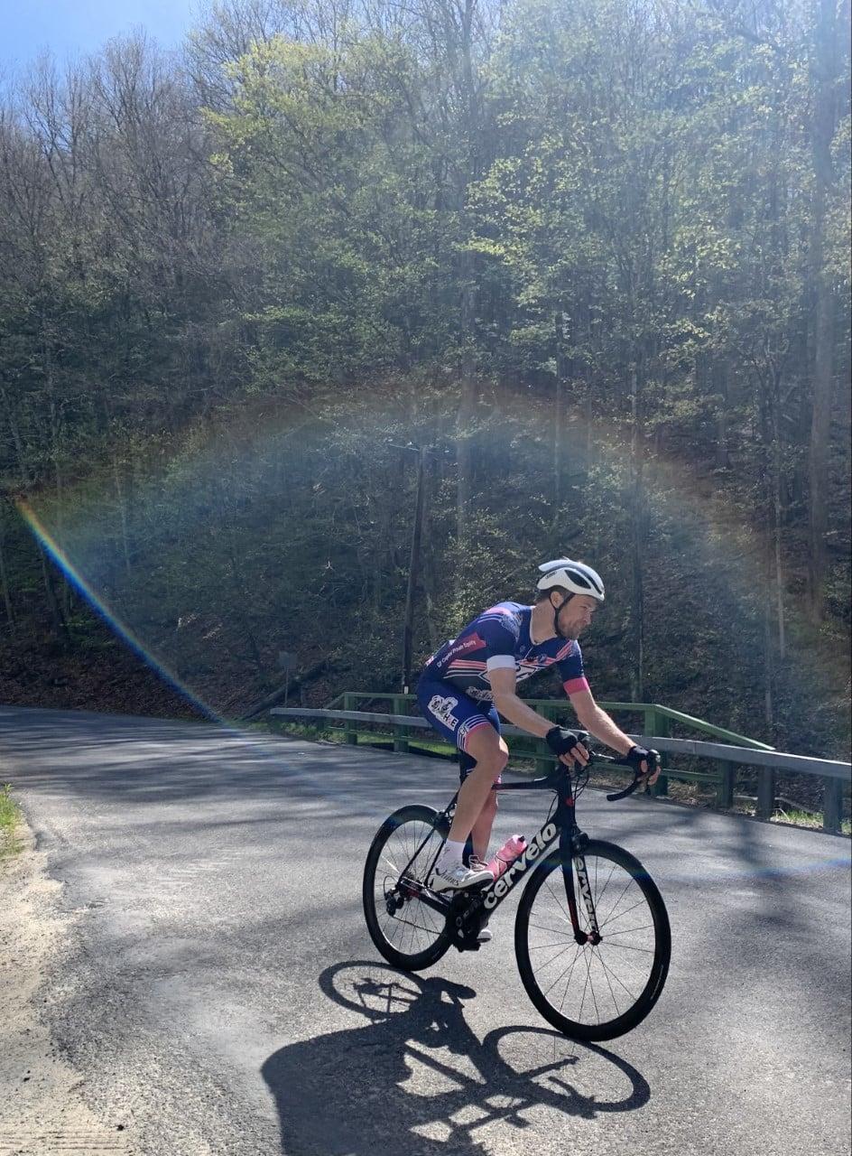 Justin on a bike outside, there is a rainbow above him