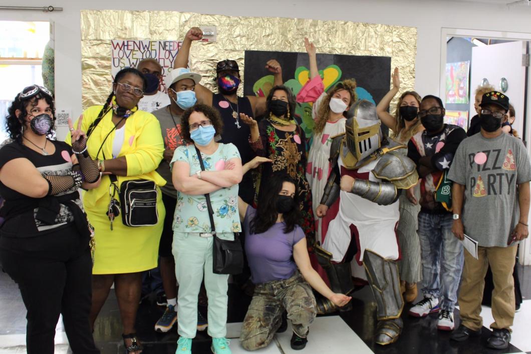  Large group of YAI artists wearing masks in front of their Spring Break Art Fair booth.