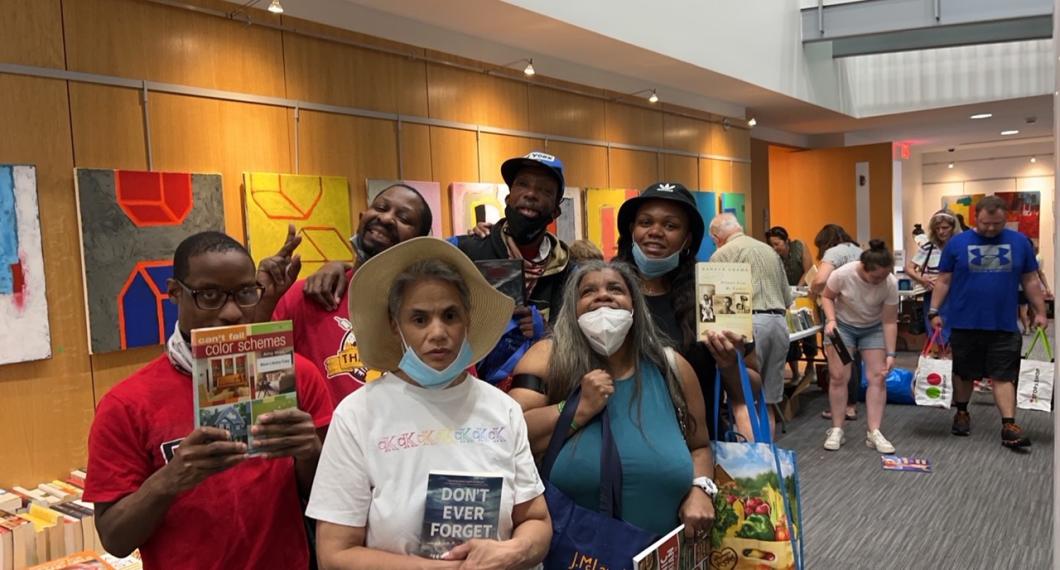 Group of people hold up books at the library