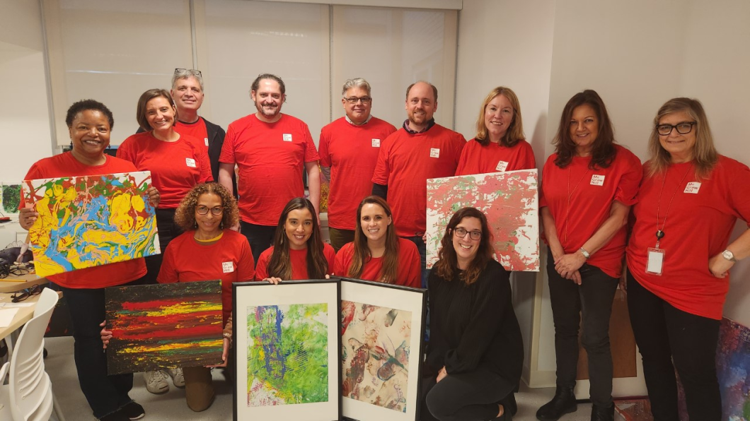 Group of McGraw Hill volunteers post with Megan holding some art pieces