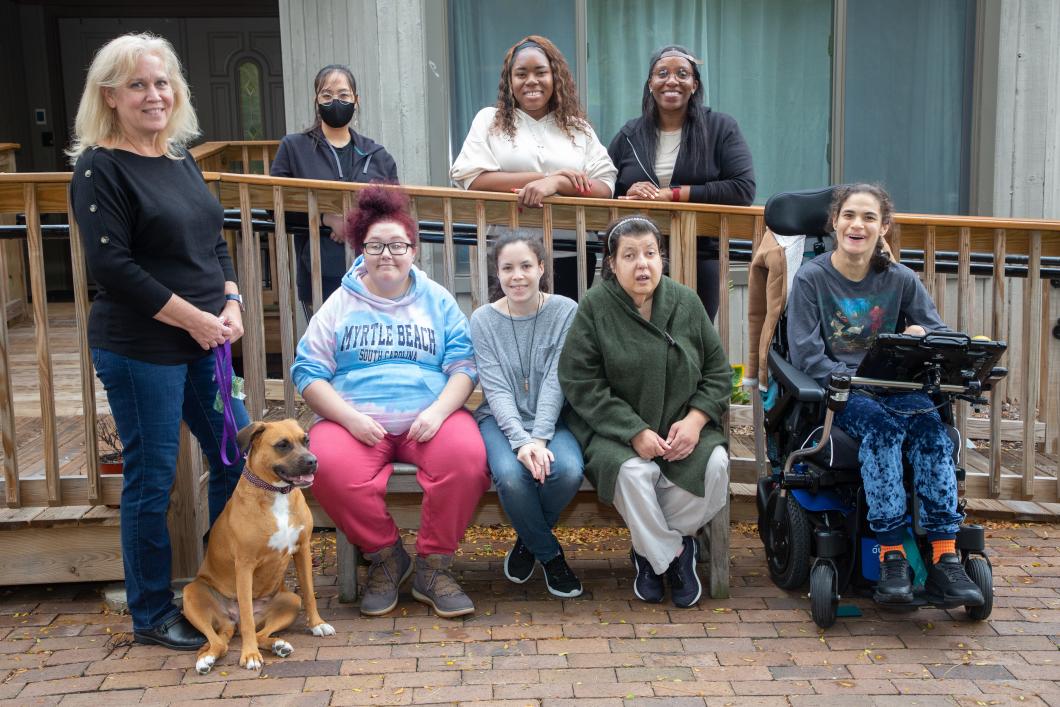 Group picture of residents and staff from Lady Godiva, a YAI residence, with Nena, their foster dog