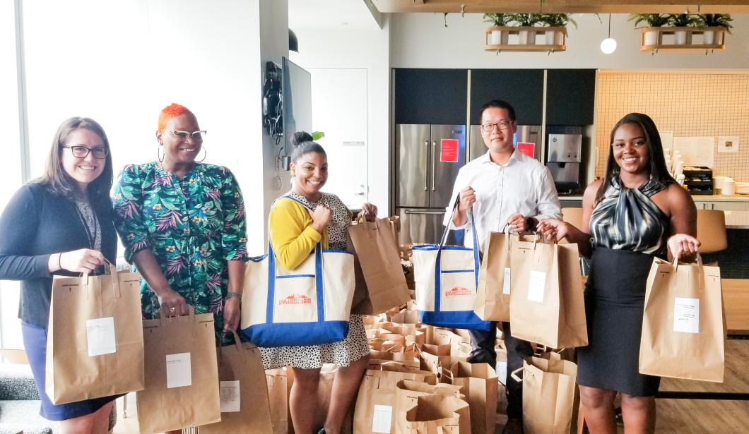 Group of volunteers hold a variety of bags with t-shirts for YAI