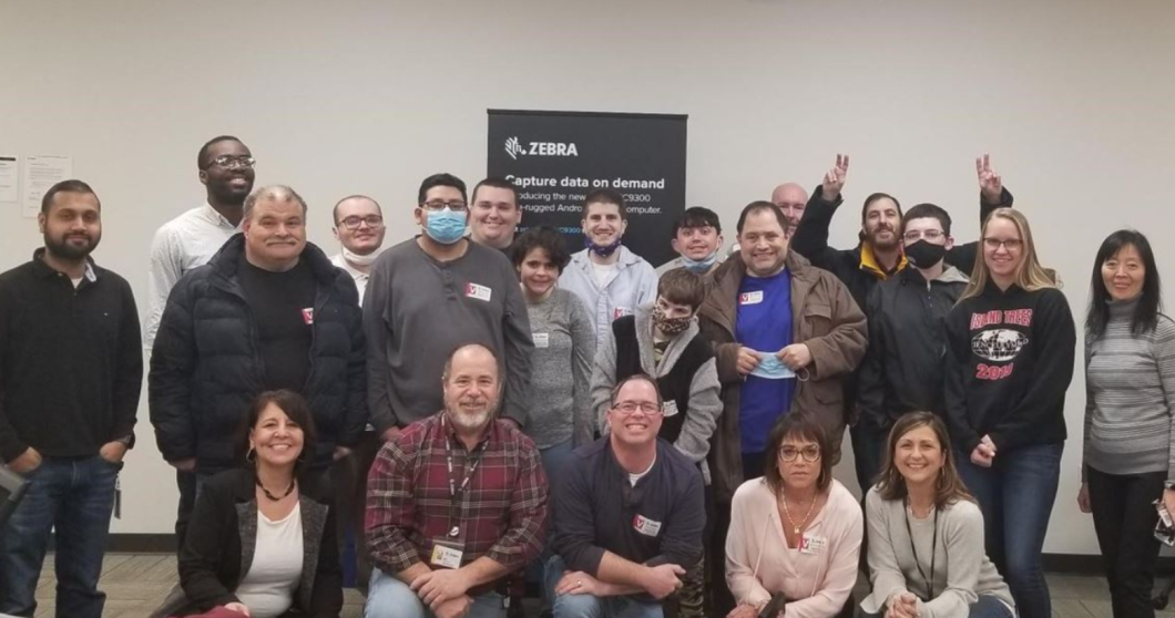 Group of people pose in front of a sign that says Zebra