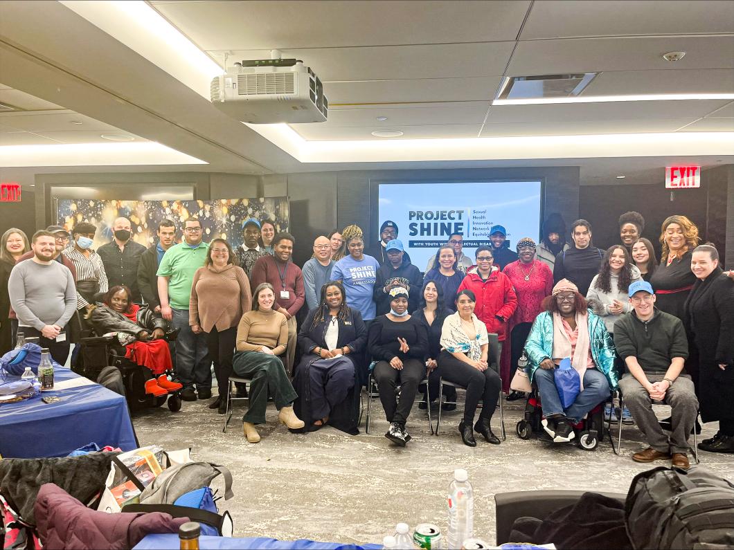 Large group of people gather standing and sitting for a photo.