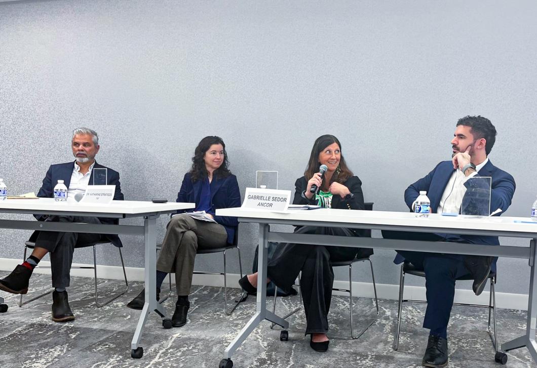 4 people sit at desks for the panel