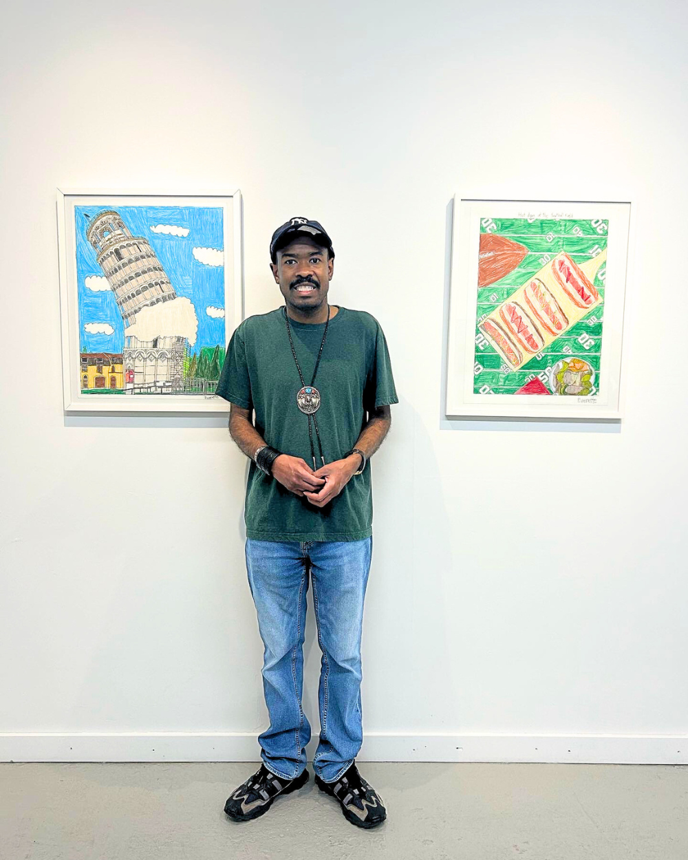 Everette Ball stands between two of his pieces that are on a wall behind him