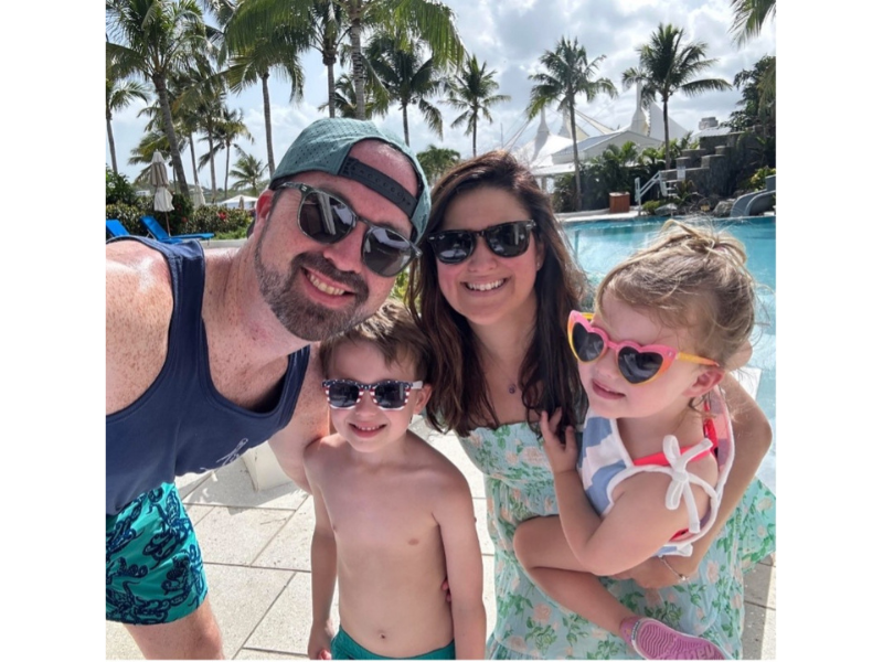 Kevin and his family pose for a selfie. They are by a pool and smiling