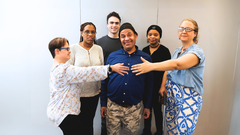 Group of people stand around one another in a group hug pose
