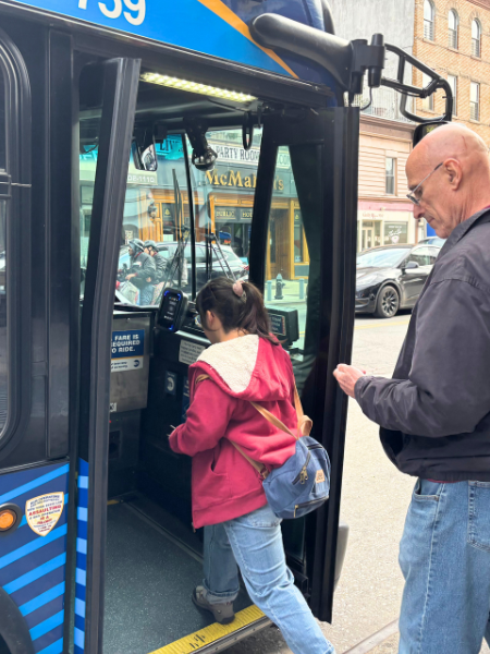 Lily boarding the bus with her father behind her.