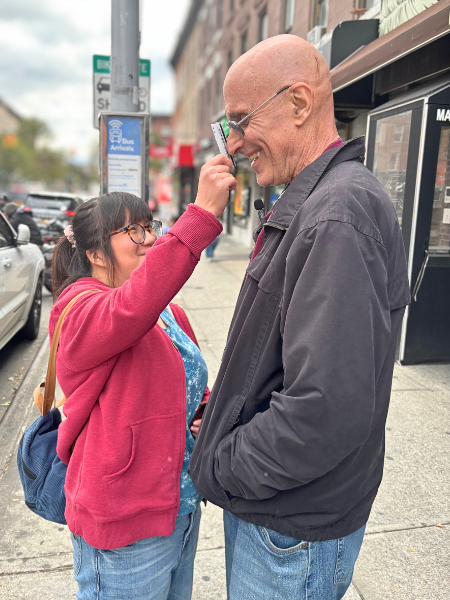 Lily reaching up to her father to bop his nose with her metrocard