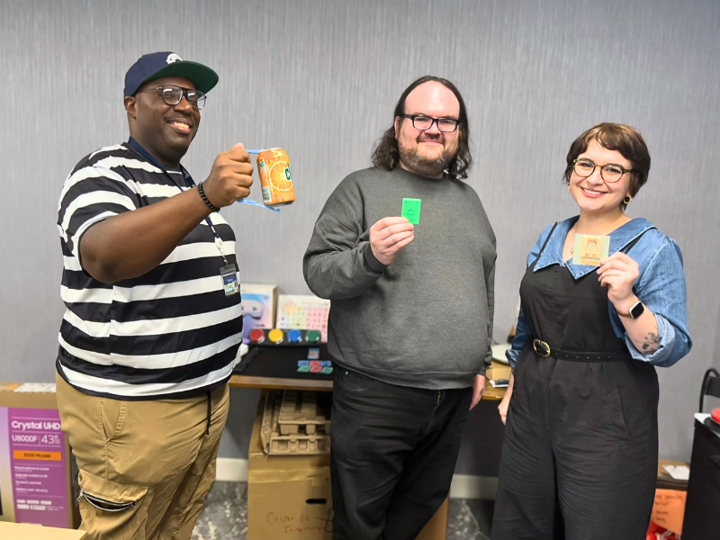 Three people pose for photo holding up various bits of technology.