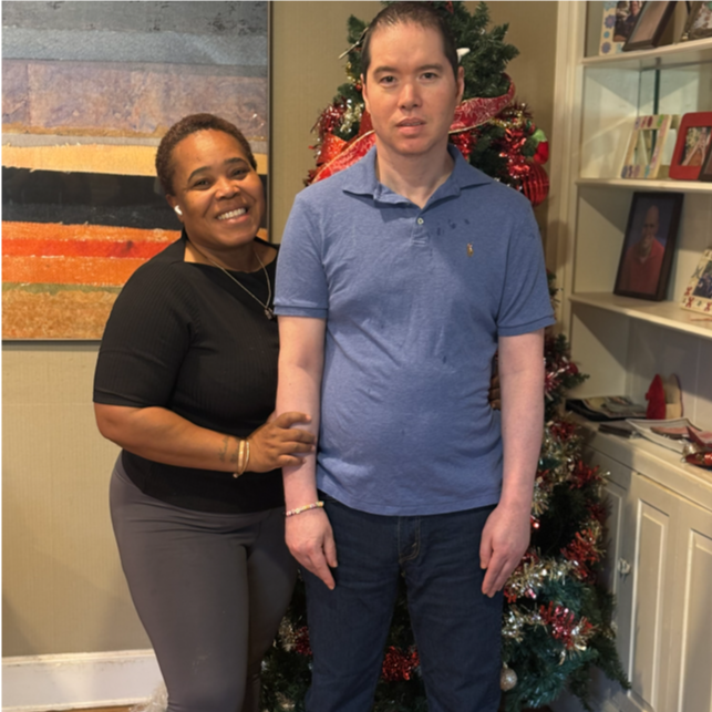 Two people standing in front of a decorated Christmas tree in a living room