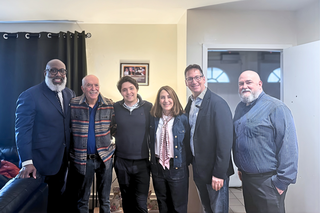 a group of people stand in line side by side for photo in front of a plaque at the Goodman Residence