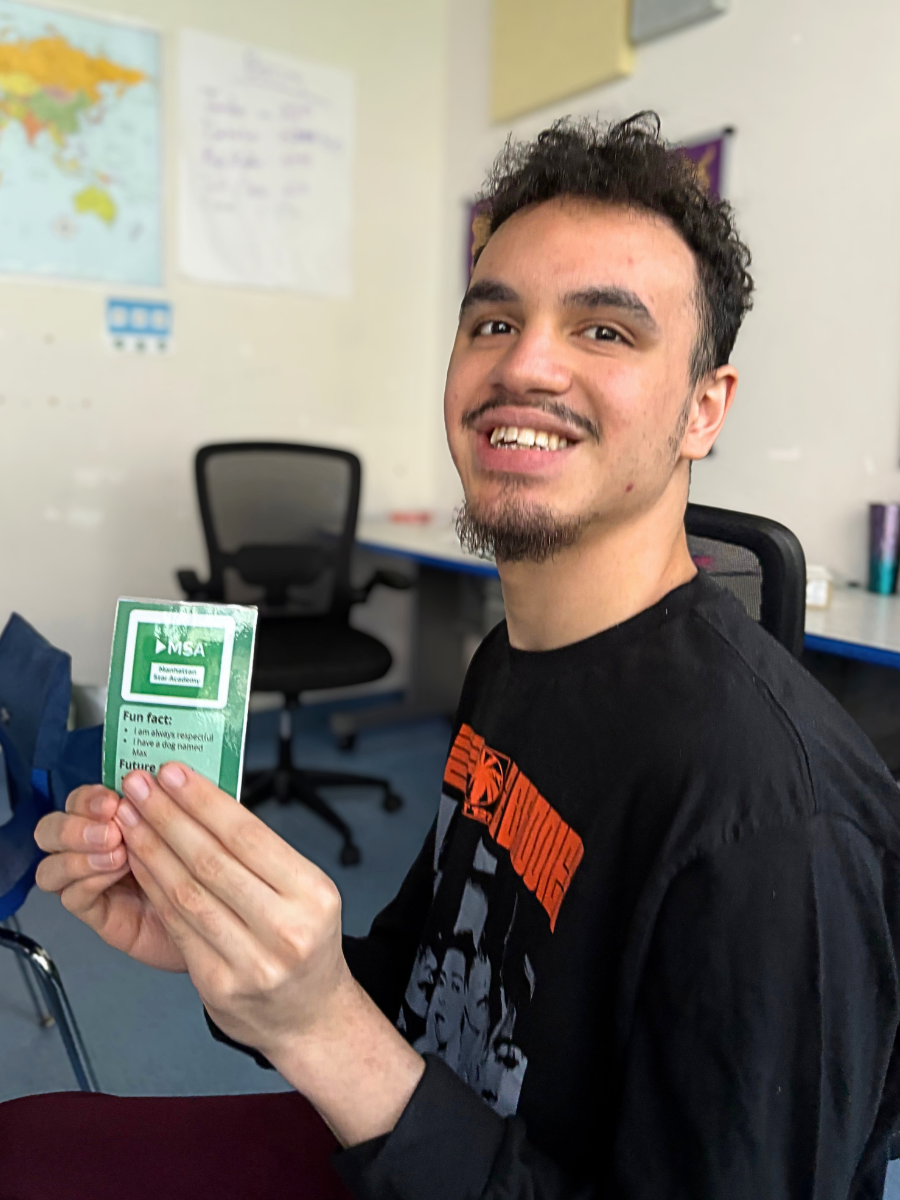 Jalil holds up a trading card he and smiles for a photo