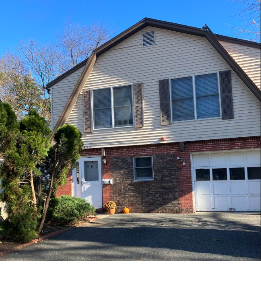 Exterior of a house with 2 large top windows and a garage door