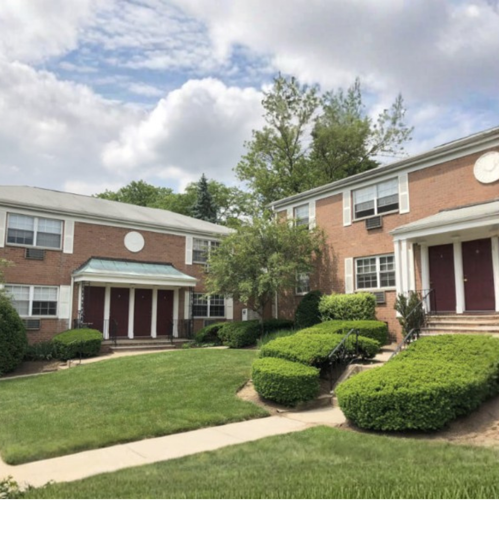 Exterior of 2 floor apartment buildings with a green lawn and bushes outside