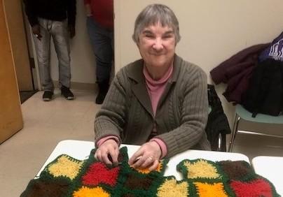 woman with colorful crocheted blanket laid out in front of her