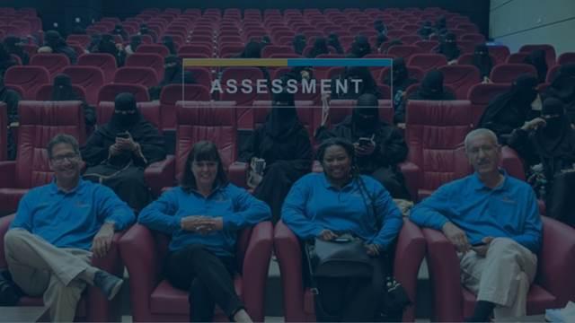 4 YAI staff members sit together in theatre seating, the word "Assessment" is on the image